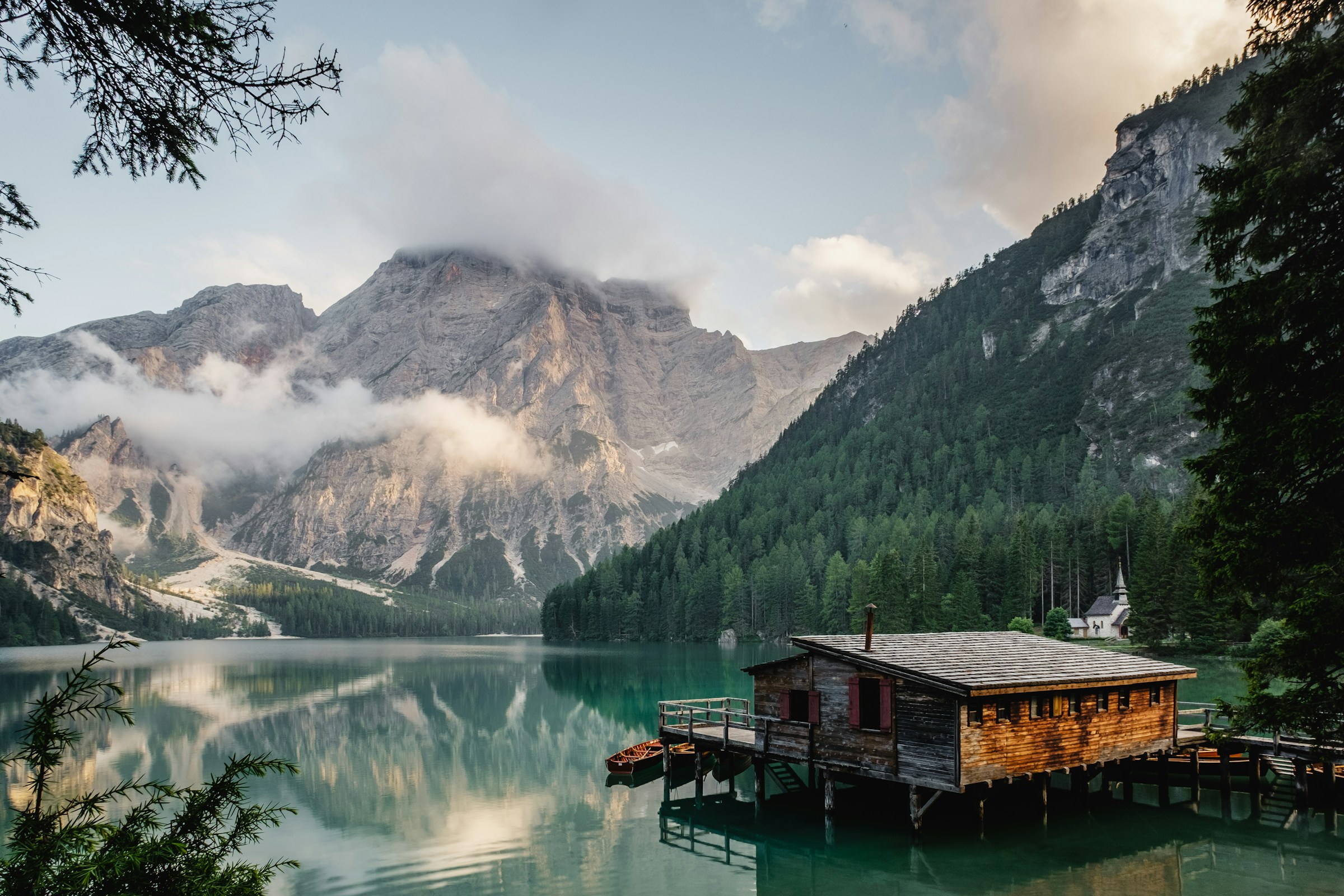 An open alpine valley with mountains reflected in a still lake